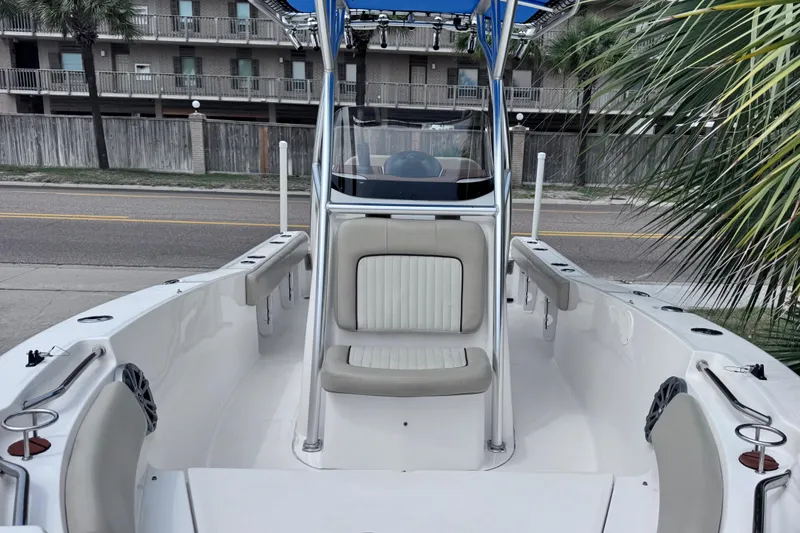 Slide: The Image of 2018 Sea Fox 206 Commander boat interior with seating, docked near a street and palm trees. - 17