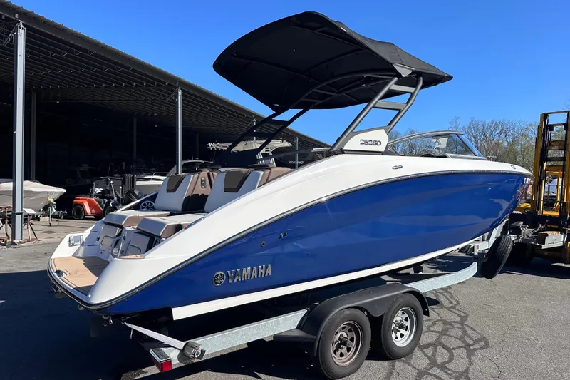 Slide: The Image of 2021 Yamaha Boats 252SD in blue and white on a trailer, parked outdoors. - 3