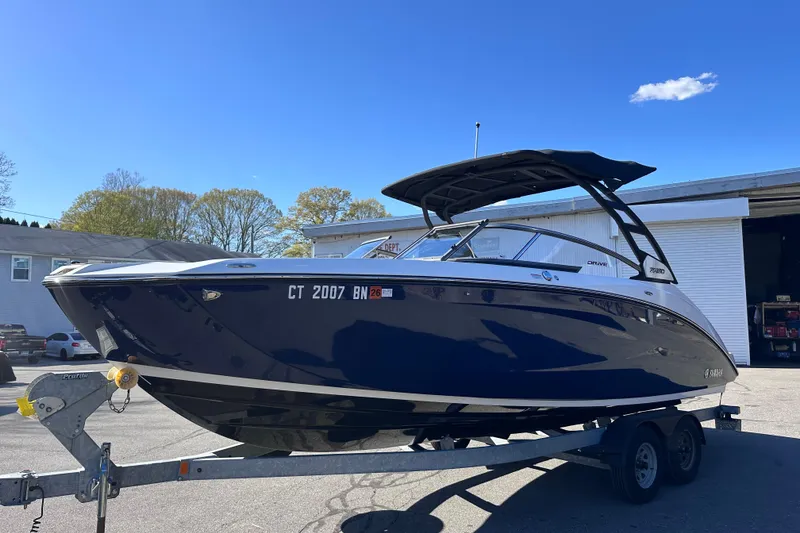 Slide: The Image of 2021 Yamaha Boats 252SD on trailer, sleek design, parked outdoors under clear blue sky. - 4