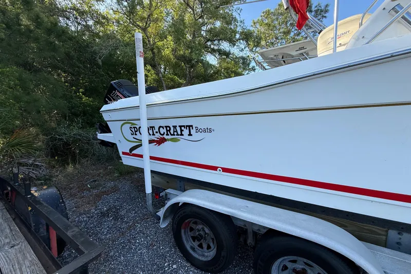 Slide: The Image of 2000 Sport-Craft 241 Walk Around boat on trailer, parked near trees. - 10