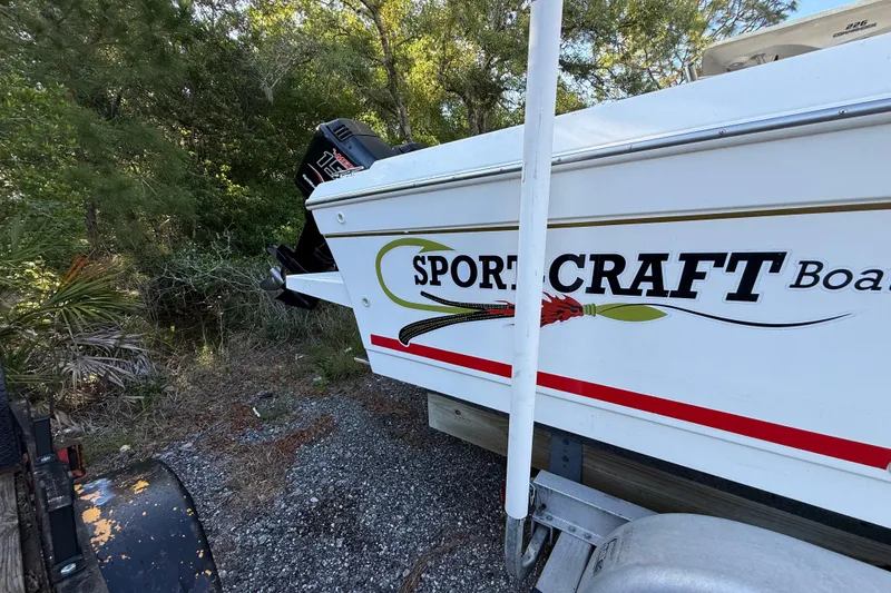 Slide: The Image of 2000 Sport-Craft 241 Walk Around boat on trailer, parked in wooded area. - 11