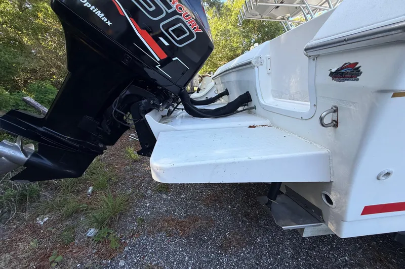 Slide: The Image of 2000 Sport-Craft 241 Walk Around boat with Mercury engine, parked on gravel. - 13