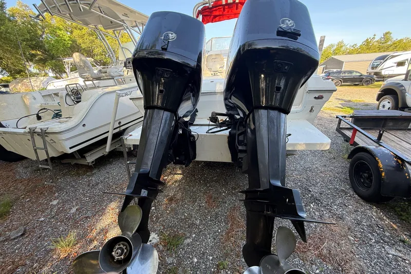 Slide: The Image of 2000 Sport-Craft 241 Walk Around boat with dual outboard motors, parked on gravel. - 15