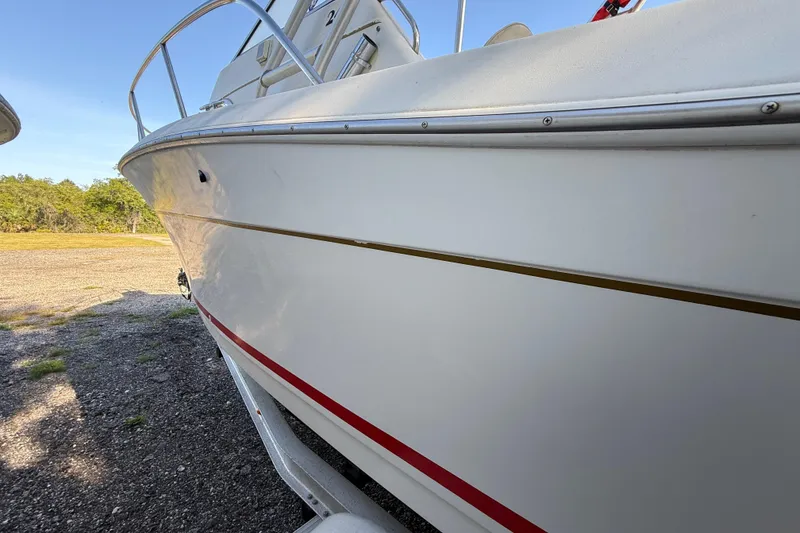 Slide: The Image of 2000 Sport-Craft 241 Walk Around boat on trailer, side view with red stripe detailing. - 24