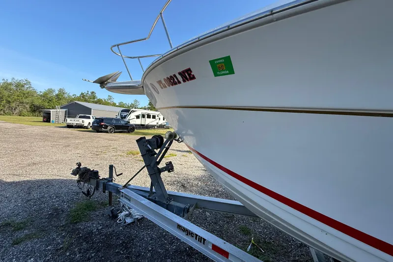 Slide: The Image of 2000 Sport-Craft 241 Walk Around boat on trailer, parked outdoors with vehicles in background. - 27