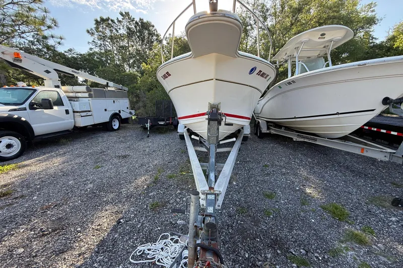 Slide: The Image of 2000 Sport-Craft 241 Walk Around boat on trailer, parked beside utility truck and another boat. - 3
