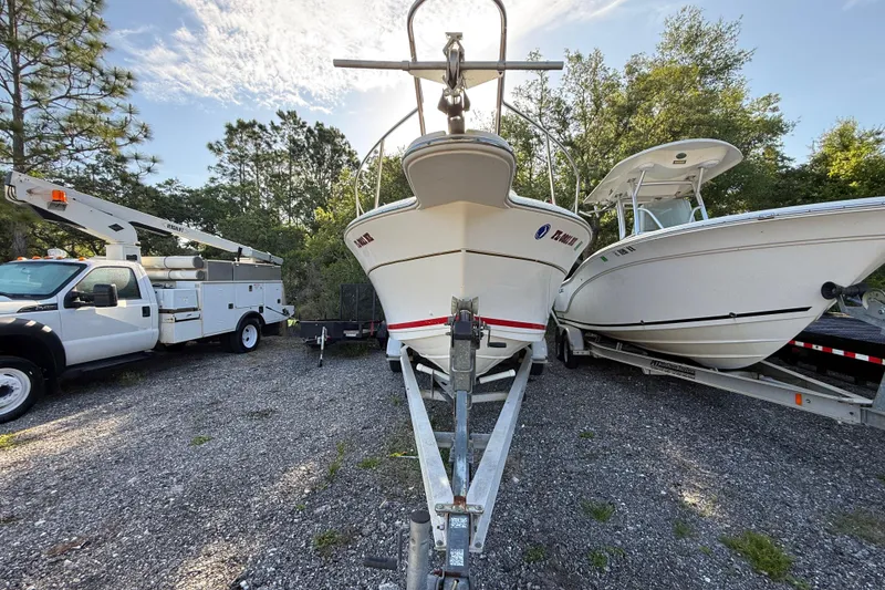 Slide: The Image of 2000 Sport-Craft 241 Walk Around boat on trailer, parked beside a utility truck and another boat. - 4