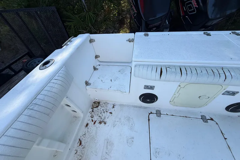 Slide: The Image of 2000 Sport-Craft 241 Walk Around boat interior with worn seating and storage compartments. - 46