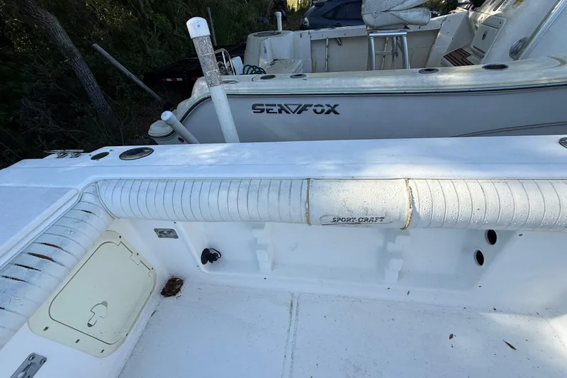 Slide: The Image of 2000 Sport-Craft 241 Walk Around boat interior with white seating and storage compartments. - 49