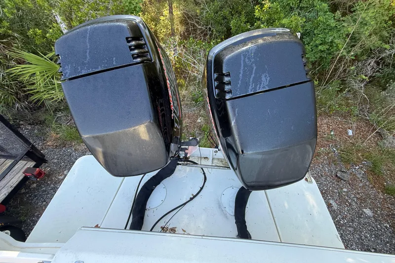 Slide: The Image of Twin outboard motors on a 2000 Sport-Craft 241 Walk Around boat, surrounded by greenery. - 53