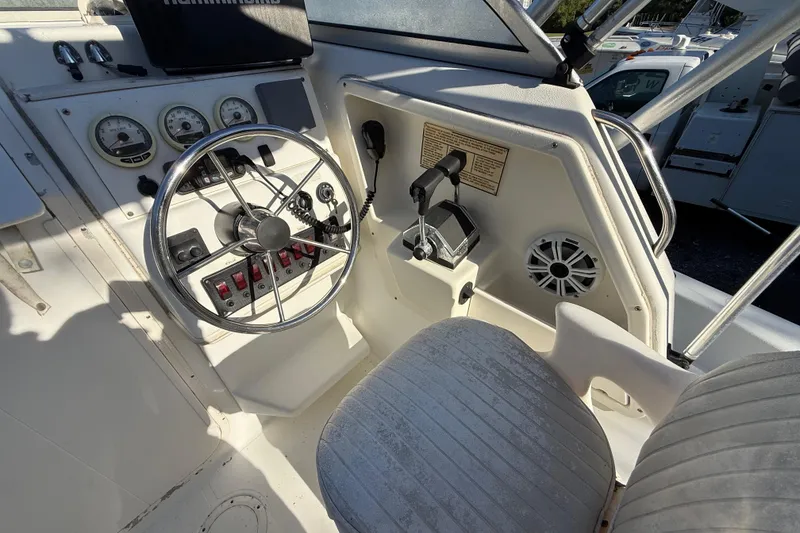 Slide: The Image of 2000 Sport-Craft 241 Walk Around boat cockpit with steering wheel and control panel. - 57