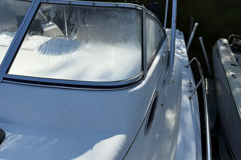Slide: The Image of 2000 Sport-Craft 241 Walk Around boat with dew-covered windshield and sleek white exterior. - 89