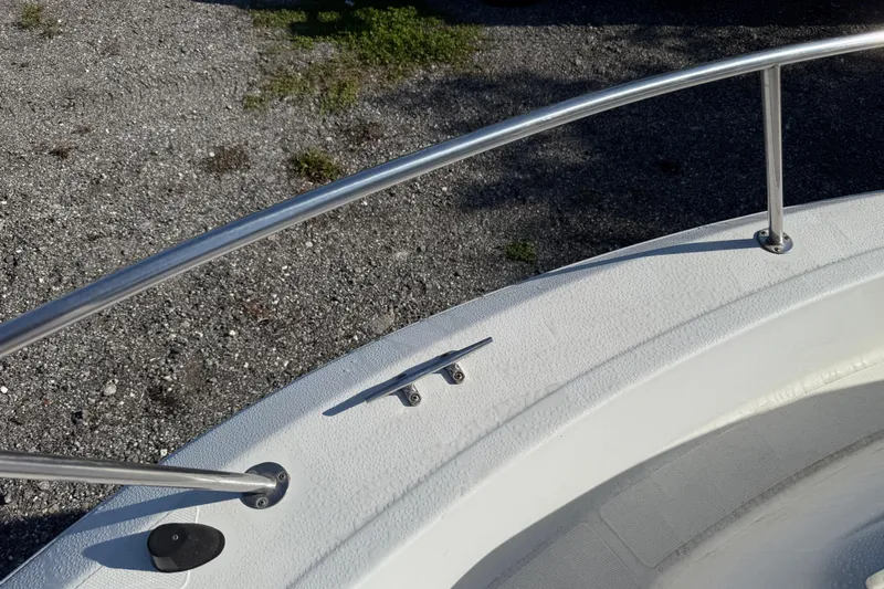 Slide: The Image of 2000 Sport-Craft 241 Walk Around boat deck with railing and cleat, on gravel surface. - 90