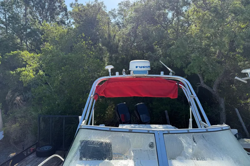 Slide: The Image of 2000 Sport-Craft 241 Walk Around boat with red canopy, surrounded by lush greenery. - 94