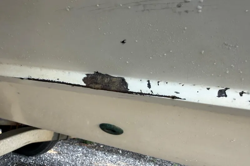 Slide: The Image of Close-up of 2000 Sport-Craft 241 Walk Around boat hull with visible paint damage. - 98
