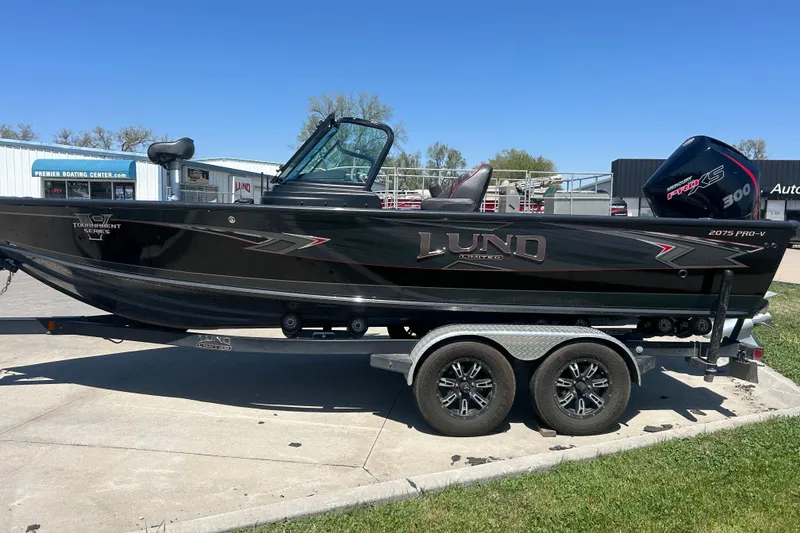 The Image of 2021 Lund 2075 Pro-V Limited boat on trailer, parked outdoors under clear blue sky. - 1