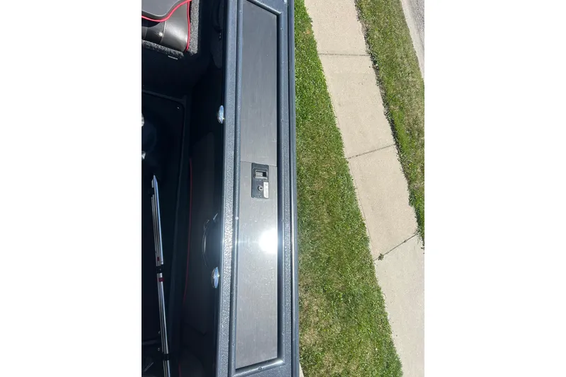 Slide: The Image of 2021 Lund 2075 Pro-V Limited boat storage compartment with lock, adjacent to grassy sidewalk. - 22