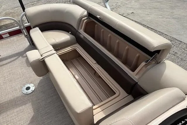 Slide: The Image of 2019 Sun Tracker SportFish 22 DLX boat with open storage compartments and beige seating. - 10