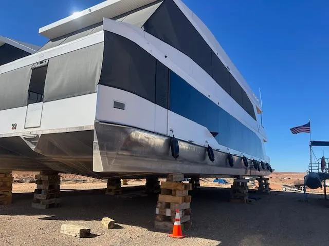 The Image of Modern Adonia Ovation houseboat elevated on blocks, 2023 model, with clear blue sky background. - 0