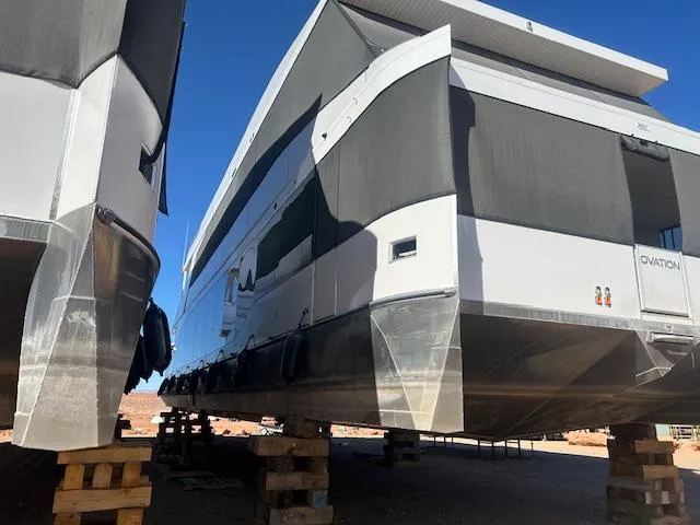 Slide: The Image of Modern Adonia Ovation houseboats on blocks, 2023 model, under clear blue sky. - 5