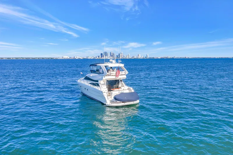 Slide: The Image of 2001 Neptunus 56 Flybridge yacht on open sea with city skyline backdrop. - 11