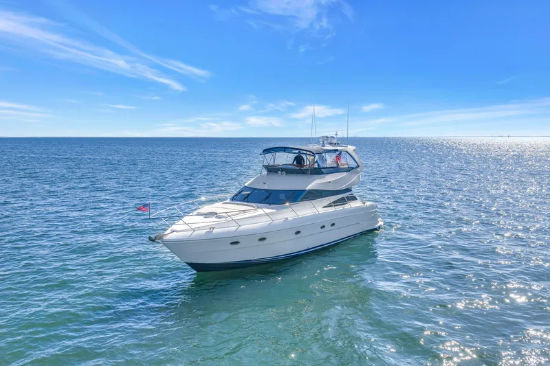 Slide: The Image of Luxury 2001 Neptunus 56 Flybridge yacht cruising on open sea under clear blue sky. - 12