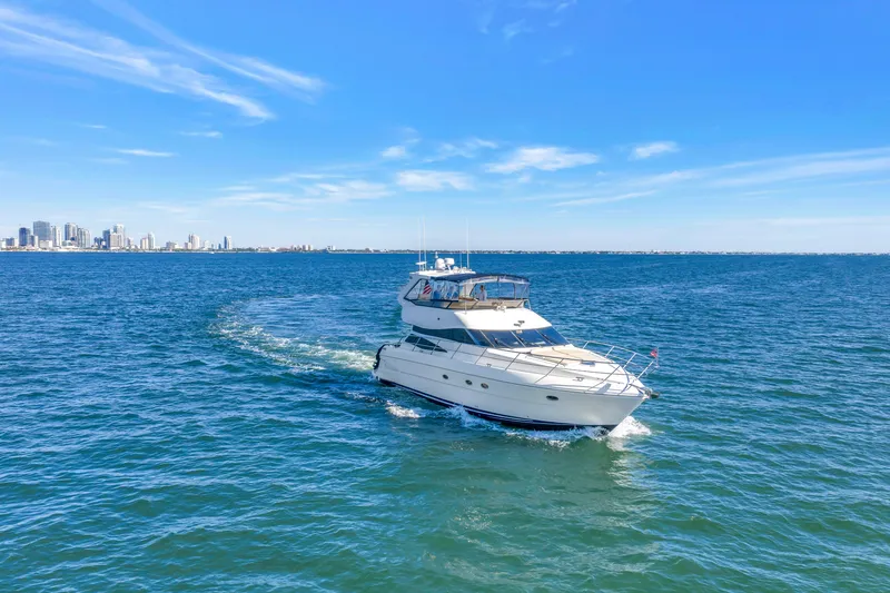 Slide: The Image of 2001 Neptunus 56 Flybridge yacht cruising on open water with city skyline in background. - 9