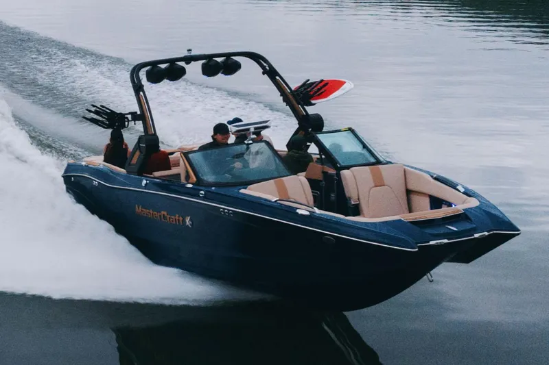 Slide: The Image of Manufacturer Provided Image: 2025 MasterCraft X24 boat cruising on a calm lake, showcasing sleek design and performance. - 2