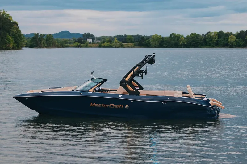 Slide: The Image of Manufacturer Provided Image: 2025 MasterCraft X24 boat on a serene lake with lush green surroundings. - 3