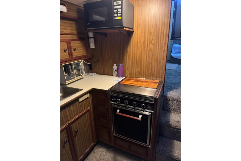 Slide: The Image of 1978 Viking 43 Aft Cabin kitchen with microwave, stove, and wooden cabinetry. - 6