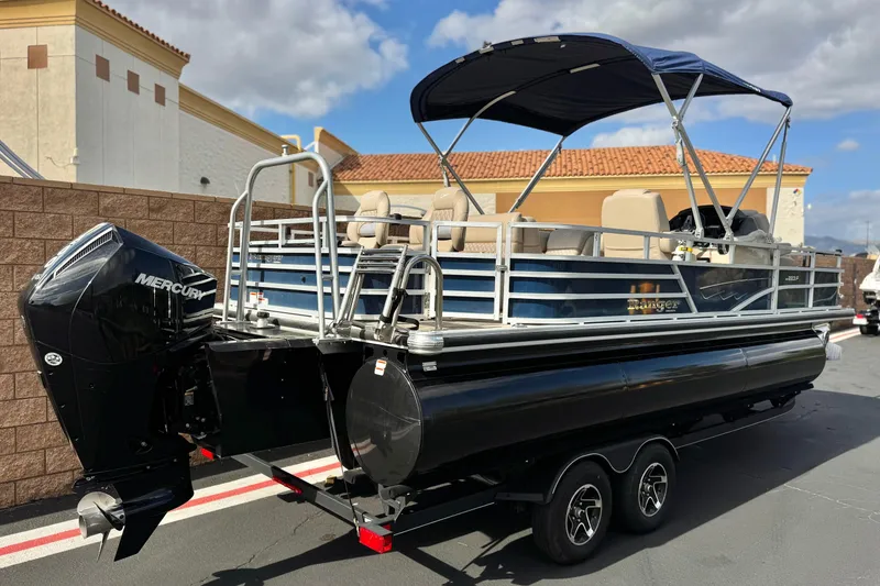 Slide: The Image of 2024 Ranger Reata 223F pontoon boat with Mercury engine, parked outdoors. - 6