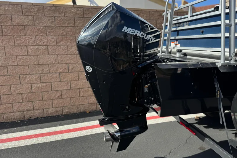 Slide: The Image of 2024 Ranger Reata 223F boat with Mercury outboard motor, parked on pavement. - 7