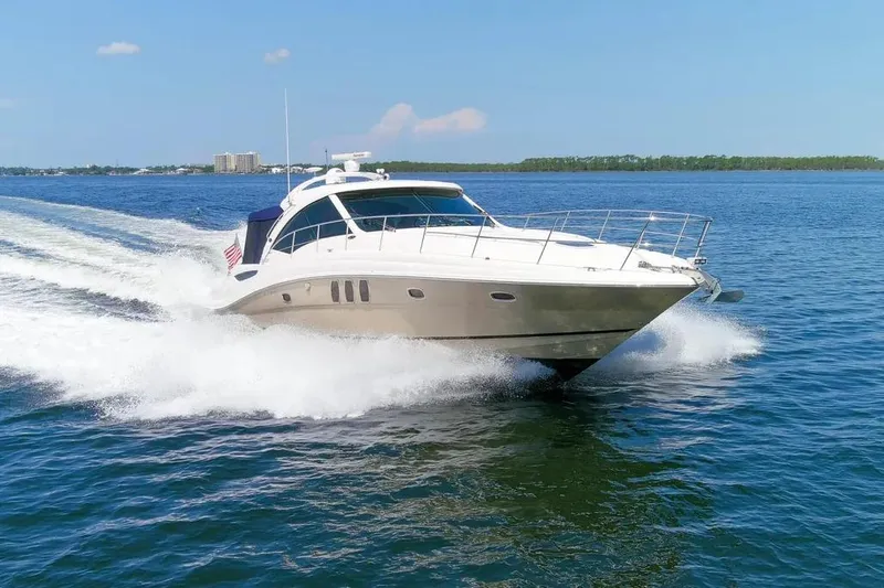The Image of 2006 Sea Ray 48 Sundancer yacht cruising on open water, clear blue sky. - 1