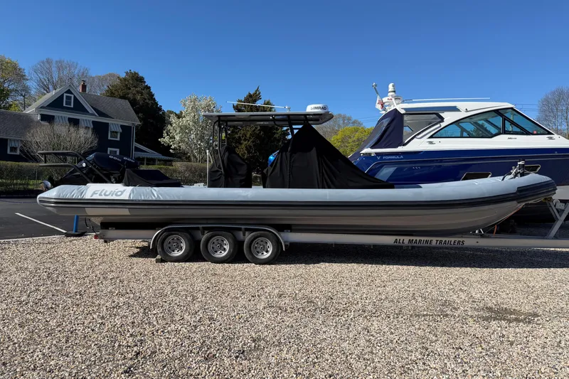 The Image of 2023 Fluid Watercraft M35 boat on trailer, parked outdoors on gravel. - 0