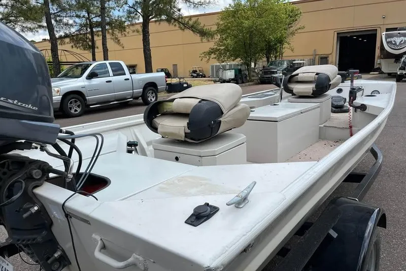 Slide: The Image of 2011 Sea-Ark Rebel 15 boat with motor, parked outdoors near trucks and trees. - 2