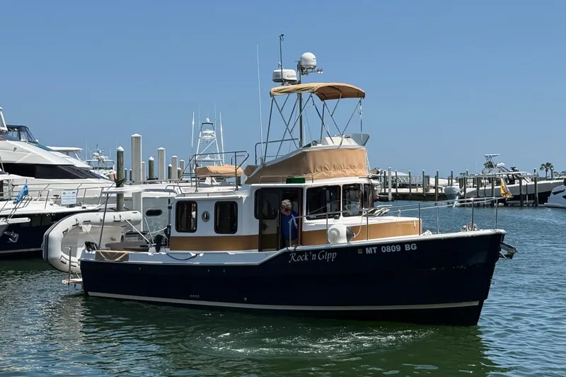 Slide: The Image of 2023 Ranger Tugs R-31 CB boat docked in a marina under clear blue skies. - 2