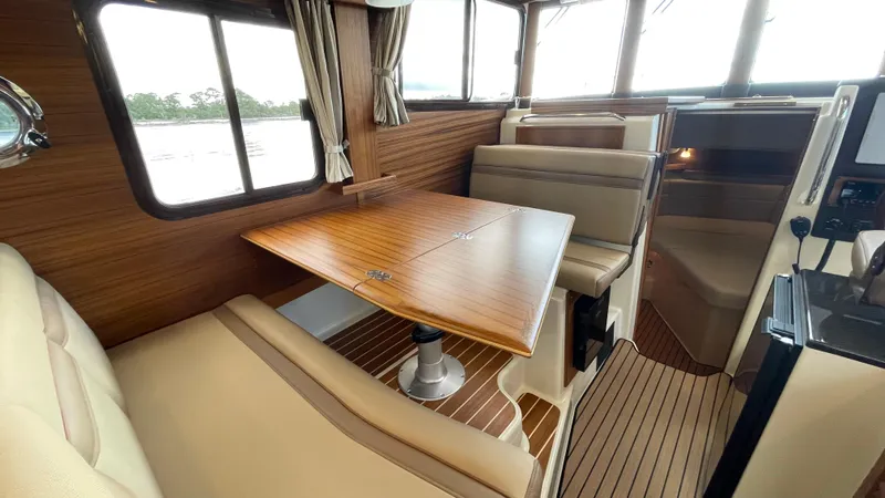 Slide: The Image of 2023 Ranger Tugs R-31 CB interior with wood accents and beige seating. - 24