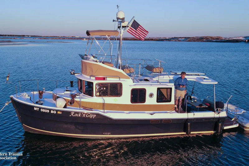Slide: The Image of 2023 Ranger Tugs R-31 CB boat on water with American flag, person onboard. - 4