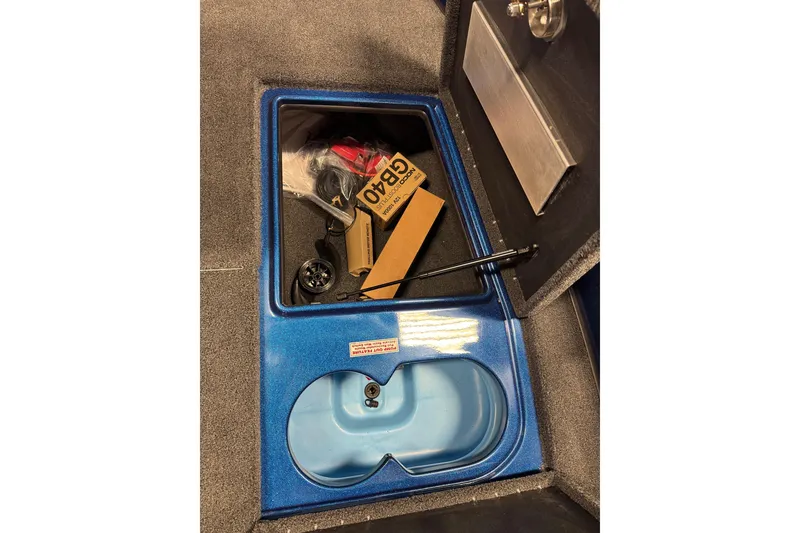 Slide: The Image of Open storage compartment in 2026 Nitro ZV19 Sport boat, showing various items inside. - 12