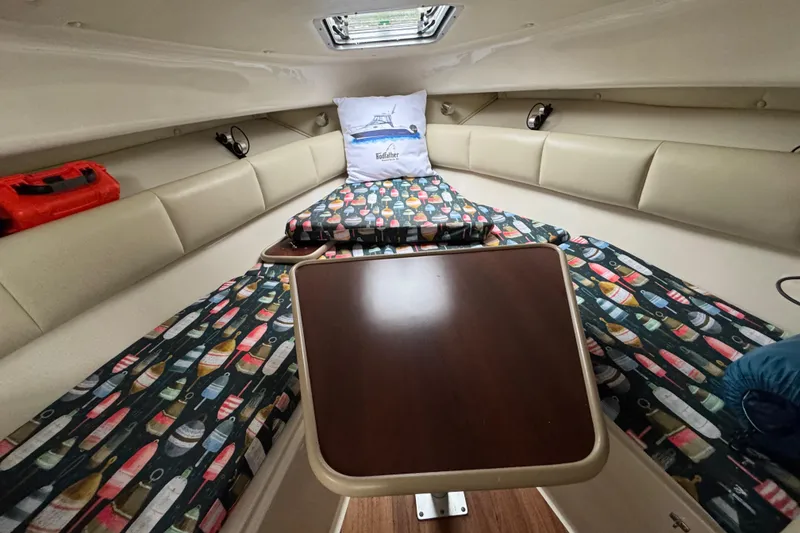 Slide: The Image of 2014 Robalo R265 Walkaround cabin interior with colorful patterned cushions and wooden table. - 12