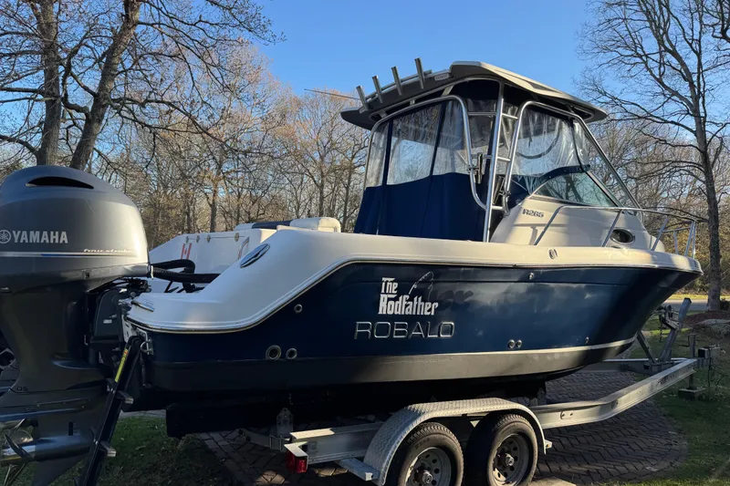Slide: The Image of 2014 Robalo R265 Walkaround boat on trailer with Yamaha engine, parked outdoors. - 2