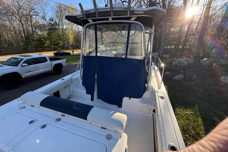 Slide: The Image of 2014 Robalo R265 Walkaround boat with blue canopy, parked near a white truck. - 5