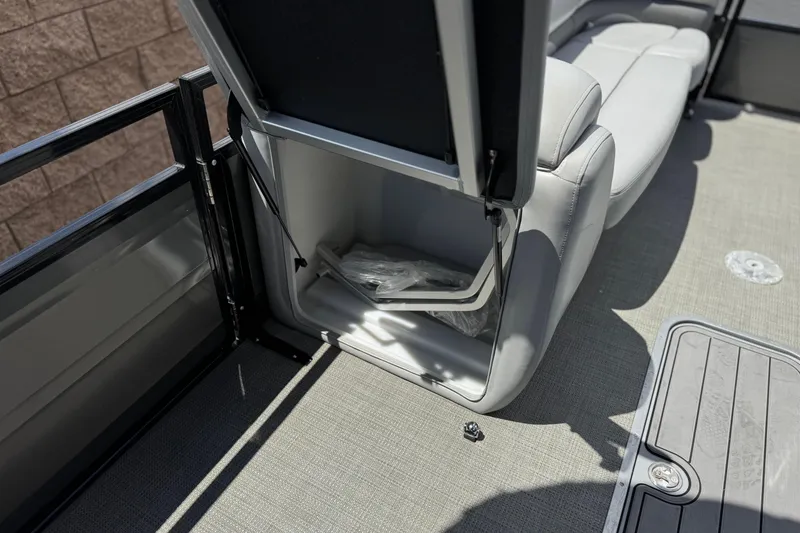 Slide: The Image of 2024 Regency 230 DL3 boat interior storage compartment with open seat and gray upholstery. - 13
