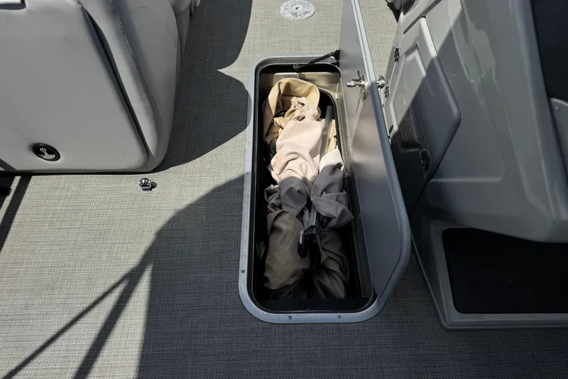 Slide: The Image of Open storage compartment on 2024 Regency 230 DL3 boat with fabric inside. - 15
