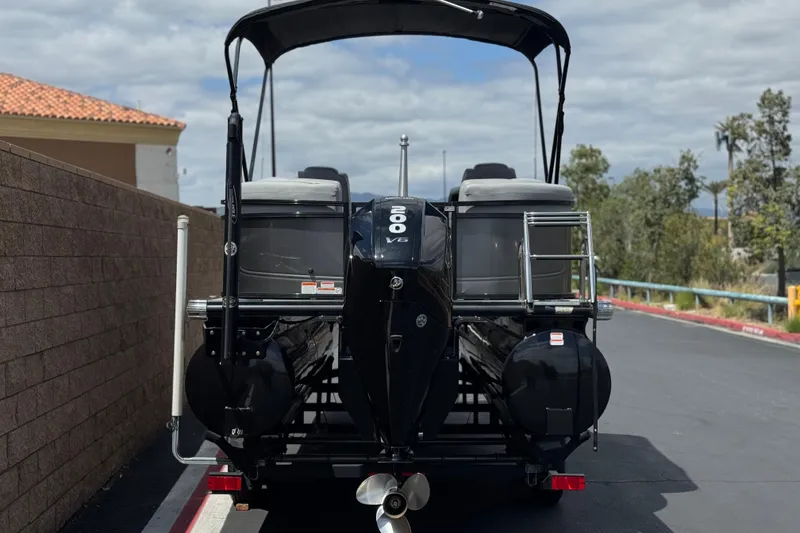 Slide: The Image of 2024 Regency 230 DL3 pontoon boat with powerful outboard motor, parked outdoors. - 5