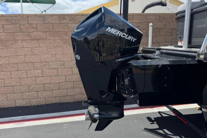 Slide: The Image of 2024 Regency 230 DL3 boat with Mercury outboard motor, parked near a brick wall. - 7