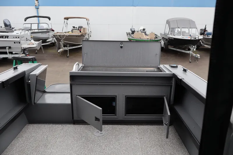 Slide: The Image of 2026 Alumaweld Horizon 24 boat interior with open storage compartments, parked among other boats. - 10