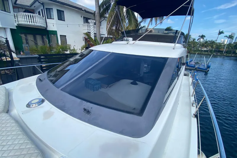 Slide: The Image of 1998 Azimut 52 yacht docked by waterfront homes, featuring sleek design and spacious deck. - 14