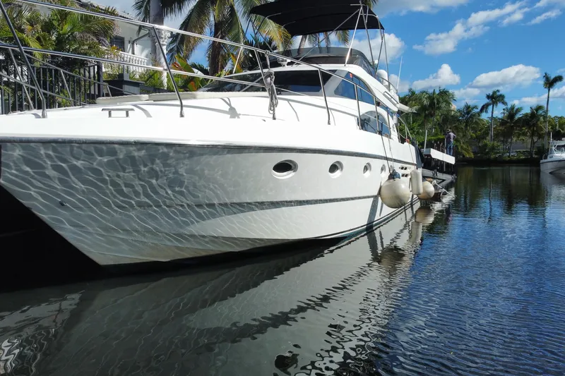 Slide: The Image of 1998 Azimut 52 yacht docked in a tropical marina, reflecting on calm water. - 17