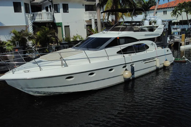 Slide: The Image of 1998 Azimut 52 yacht docked near waterfront homes, showcasing sleek design and luxury features. - 2